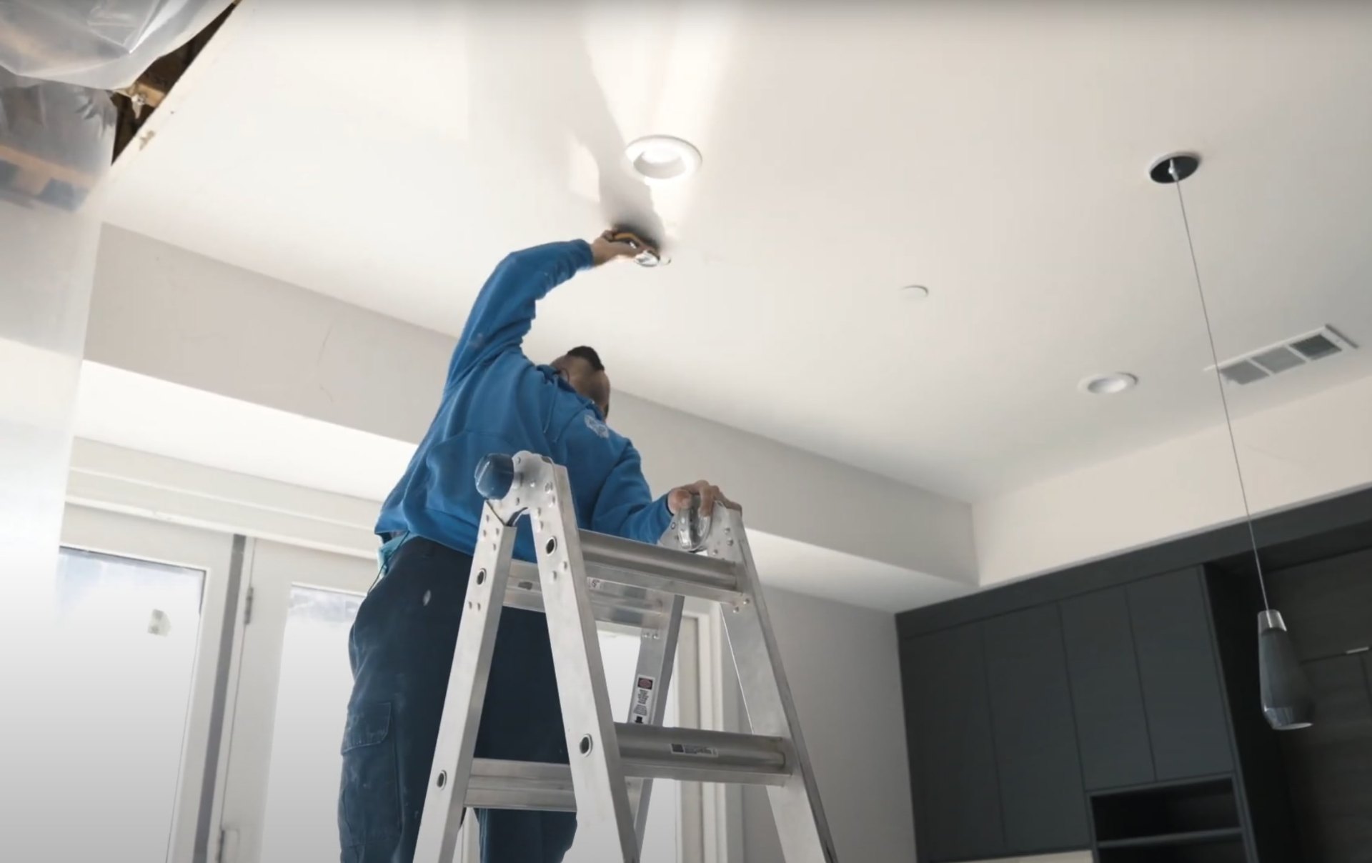 Ceiling water damage inspection and restoration Professional water damage restoration technician inspecting ceiling damage with specialized equipment